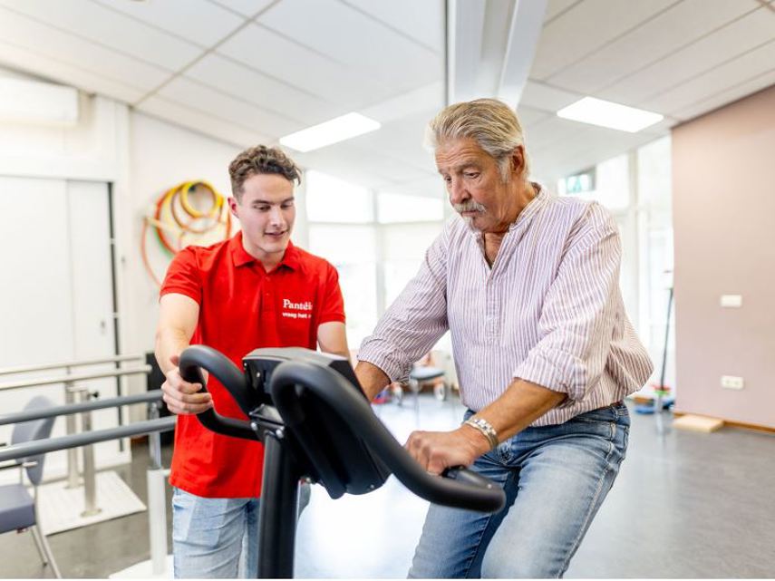 Fysiotherapeut naast klant op hometrainer