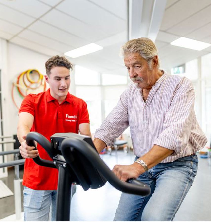 Fysiotherapeut naast klant op hometrainer