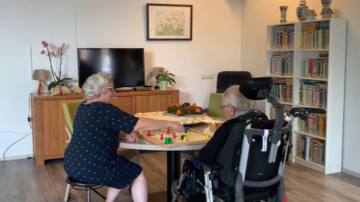 Vrouw speelt mens-erger-je-niet met man in rolstoel