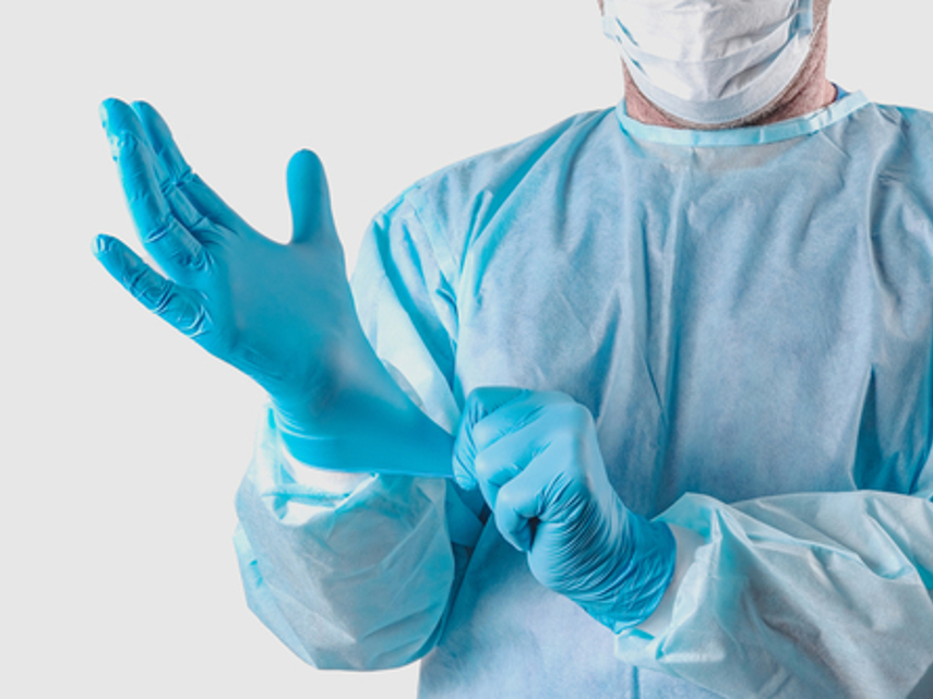 Man in beschermende kleding trekt medische handschoenen aan